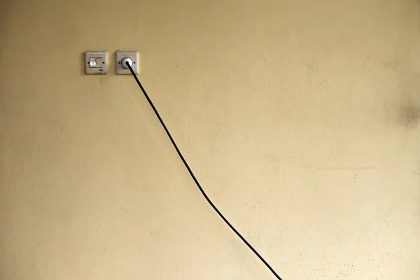 Розетка и электрический кабель через стену. Неудобное расположение электричества в доме . — стоковое фото