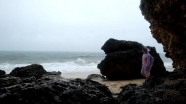 Kızıl yağmur ceket şiddetli yağmur Bali Endonezya kumsalda genç kadın