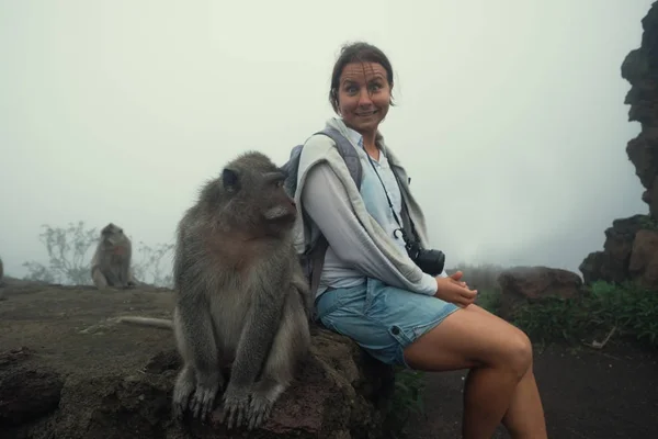 Kaukasische vrouw in een korte broek zitten in de buurt van monkey. — Stockfoto