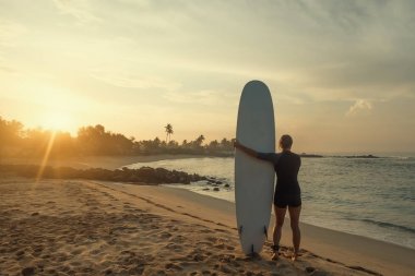 su kenarında duran ve dalgaları seyir sörf tahtası beyaz kadınla.