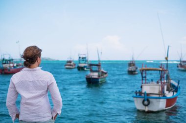 Midigama plaj üzerinde duran ve okyanus ve geleneksel renkli yerel tekneler bakarak Kafkas kadın