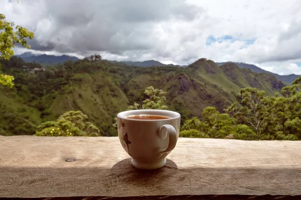 Um copo de chá quente na mesa na loja de chá e vista sobre pequenas barragens Pico no Sri Lanka . — Fotografia de Stock