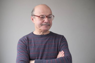 Büyük gözlüklü kıdemli İspanyol adam aşağıya bakıyor.