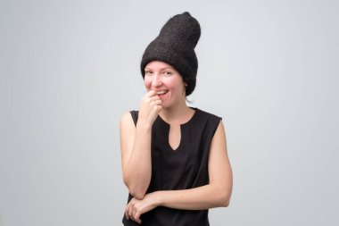 Siyah şapkalı mutlu kadın kameraya bakıp gülümsüyor..