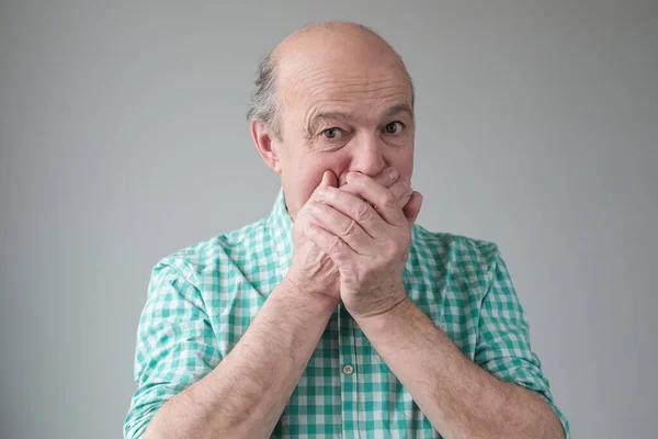 Зрелый старший латиноамериканец, прикрывающий рот рукой — стоковое фото