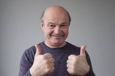 Olgun bir adam gülümseyerek parmağını kaldırır seçimini onaylar ya da tavsiye verir..