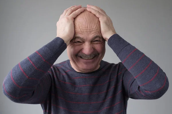 Homem hispânico sênior rindo em voz alta com os olhos fechados e a mão na cabeça — Fotografia de Stock