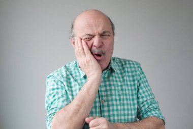 Acı çeken, yanağını eliyle tutan, kötü diş ağrısından muzdarip bir adam.
