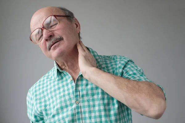 Frustrierter Senior hält sich vor grauem Hintergrund die Hand um den Hals — Stockfoto