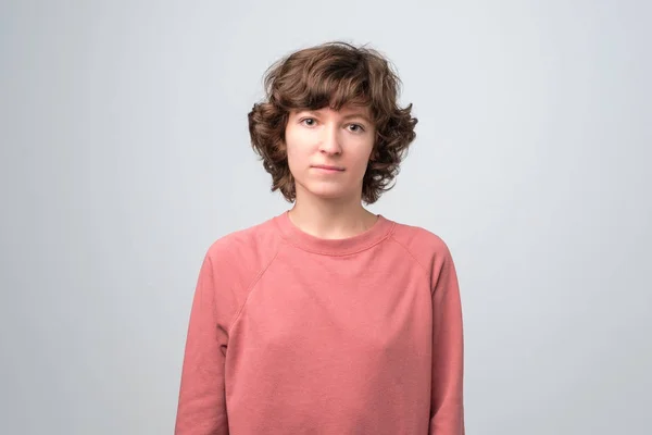 Young woman with curly hair looking at camra with boredunwilling emotion on face — Stock Photo, Image