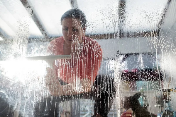 Tired woman making house chores cleaning a window