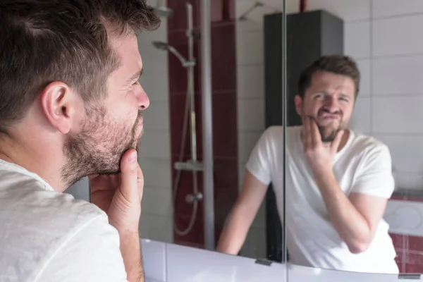 Hombre comprobar el estado de su piel en reflexión espejo —  Fotos de Stock