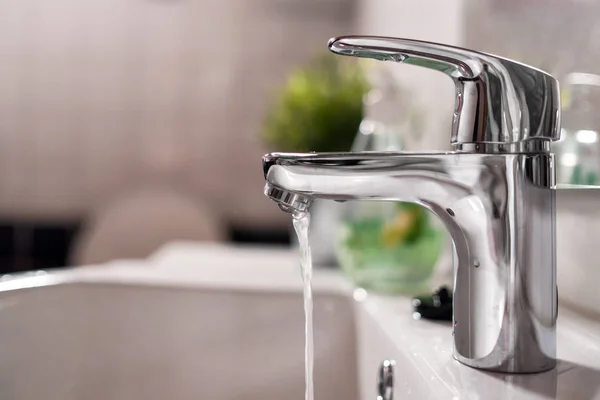 Air dingin yang mengalir dari keran di kamar mandi yang bersih — Stok Foto