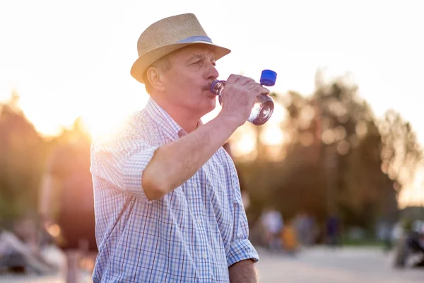 Idős férfi palackozott vizet iszik kint állva — Stock Fotó