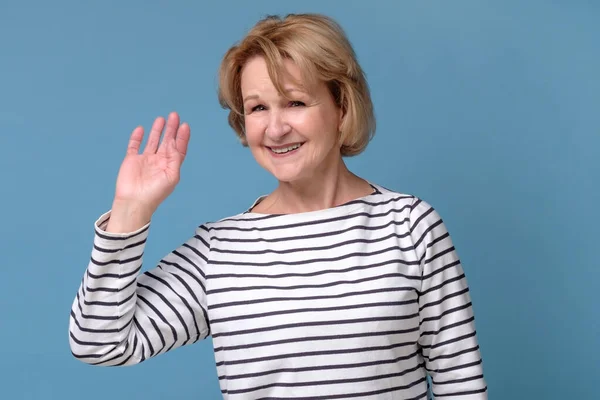 Emotionele oudere vrouw zwaaiende hand zegt hallo — Stockfoto