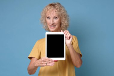 Kıdemli kadın siyah ekranlı ve gülümseyen bir tablet sergiliyor.