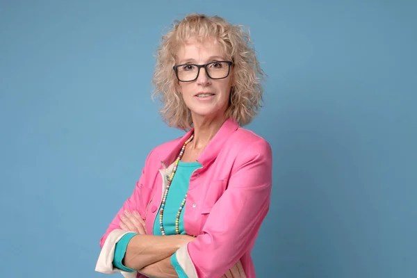 Mature woman with curly blonde hair and glasses smiling and standing confident — Stock Photo, Image