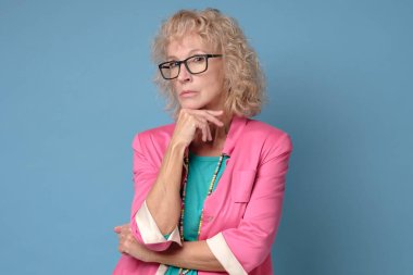 Gözlüklü, kendine güvenen öğretmen, profesyonel yönetmen kameraya bakıyor.