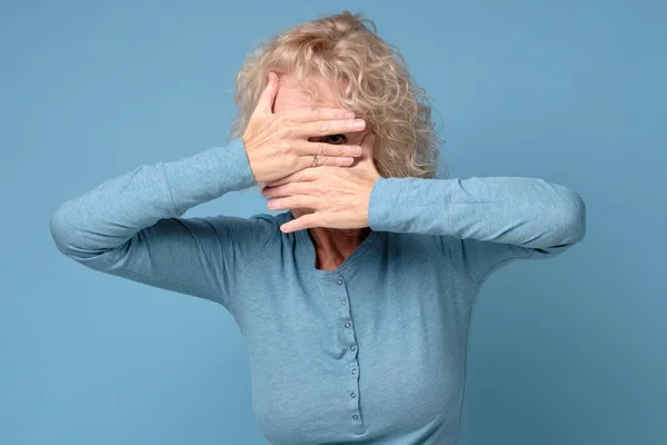Dojrzała kobieta zakrywa twarz rękami i szpiegami, zasłaniając jej oczy — Zdjęcie stockowe
