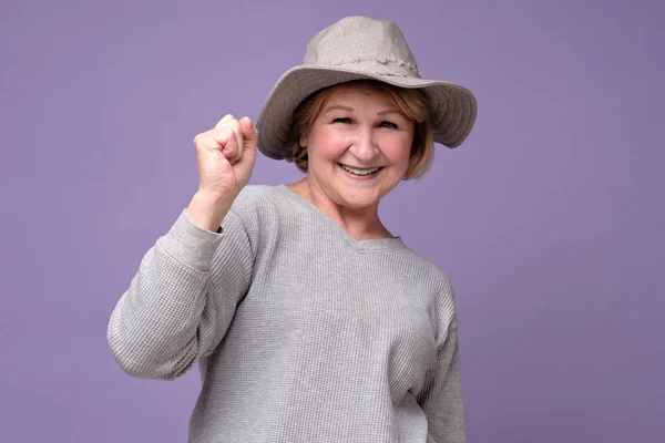 Donna anziana che indossa cappello estivo sorridente pugno in mano . — Foto Stock