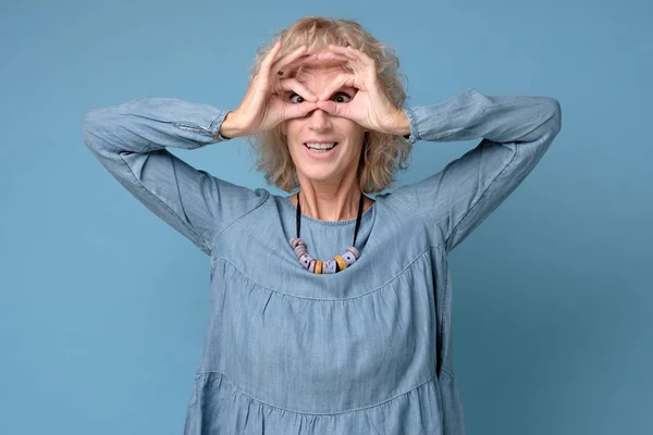 Mujer bonita sosteniendo los dedos cerca de los ojos como gafas . —  Fotos de Stock