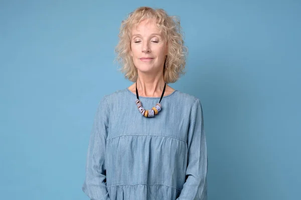 Mujer sonriente sénior positiva con los ojos cerrados de pie meditando — Foto de Stock