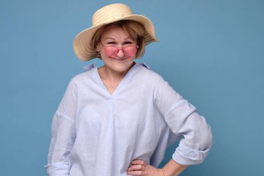 Yazlık şapkalı kadın elinde gülümseyerek kameraya tatil için poz veriyor..