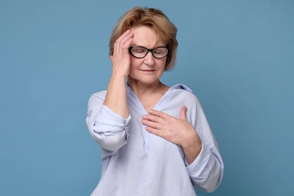 Mujer en gafas cogidas de la mano a la frente con migraña o dolor de cabeza . — Foto de Stock