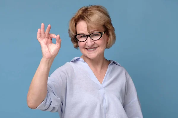 Señora mayor sonriente en gafas gestos signo perfecto . — Foto de Stock