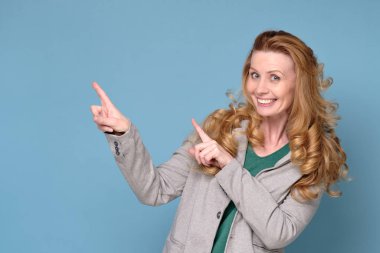 Uzun saçlı olgun bir kadın işaret ediyor.