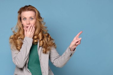 Kadın fotokopi odasını işaret ediyor, şaşırmış orta yaşlı kadın mavi duvarda..