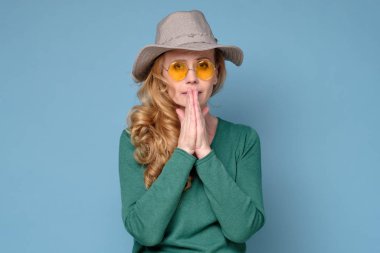 Kadın avuçlarını önünde birbirine bastırıyor, pişmanlık ifadesi var.