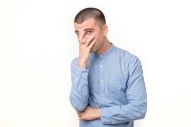 Şok olmuş ve dehşete düşmüş genç bir adam elleriyle yüzünü kapatıyor ve kameraya bakıyor.