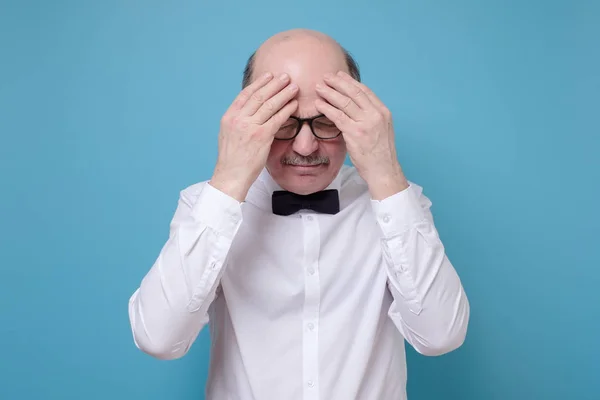 Hombre hispano mayor con gafas con dolor de cabeza cogido de la mano . — Foto de Stock