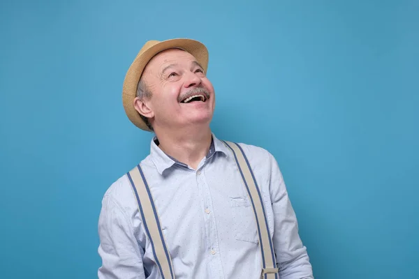 Senior feliz hombre mirando sonriendo de pie sobre fondo azul . — Foto de Stock