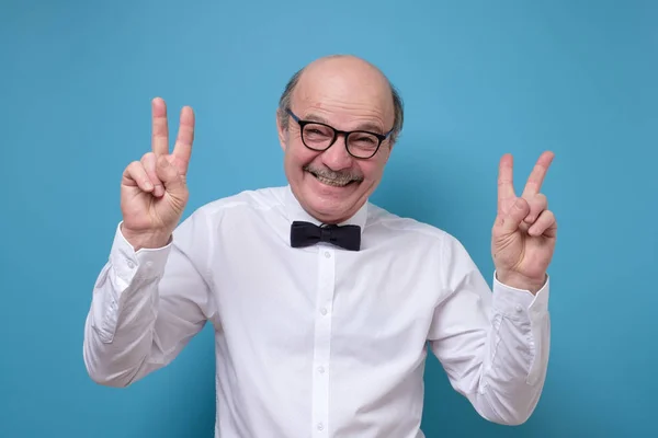 Homme hispanique senior drôle portant des lunettes souriant avec signe de victoire — Photo