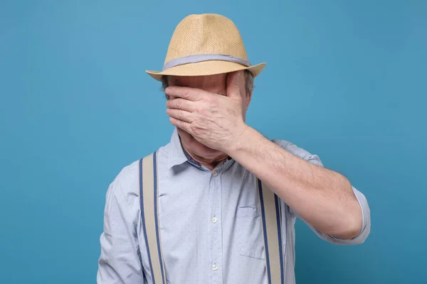 Senior man i sommar hatt täcker ögon — Stockfoto