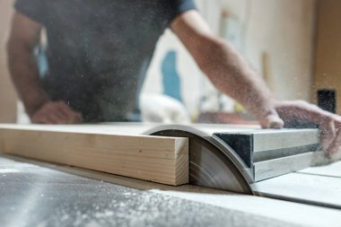 Kafkasyalı marangoz dairesel testereyle odun kesiyor ve yeni mobilyalar yapıyor.