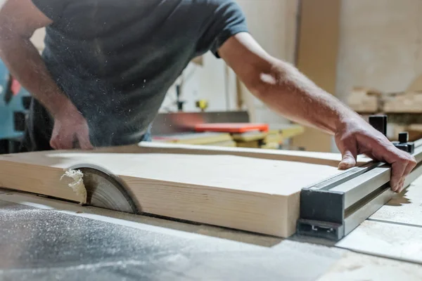 Caucasian man carpenter cutting wood with circular saw creating new furniture — Stock Photo, Image