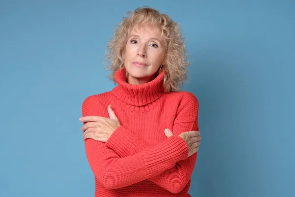 Dame âgée avec un sourire vif posant sur un fond bleu — Photo