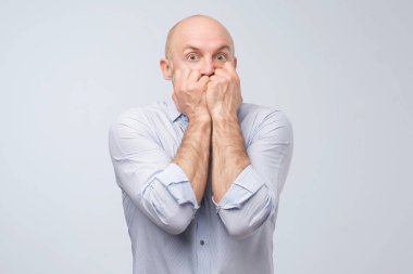 Ağzı kapalı, korkmuş, olgun bir adam. Stüdyo çekimi. Erkek hayalet görmüş..