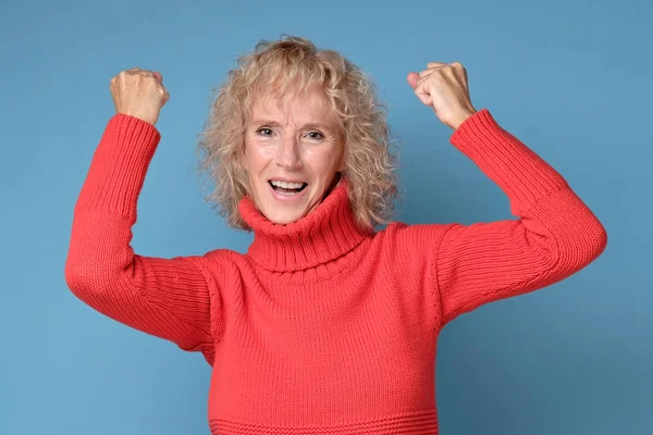Mujer mayor feliz en suéter rojo con los puños levantados —  Fotos de Stock