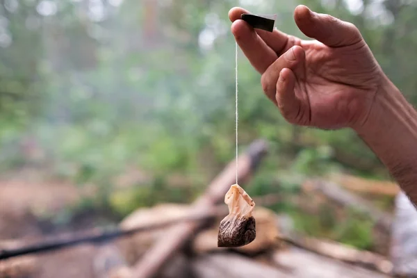 Homme tenant utilisé sachet de thé après le petit déjeuner en forêt . — Photo