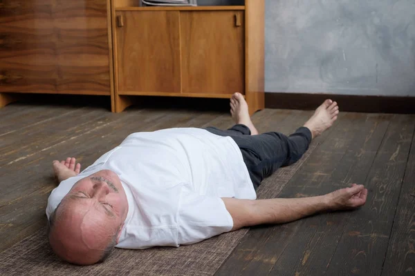 Yoga. Senior man mediterar på ett trägolv och ligger i Shavasana pose. — Stockfoto