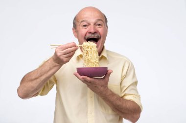 Senior bald asian man eating noodles, traditional chinese food