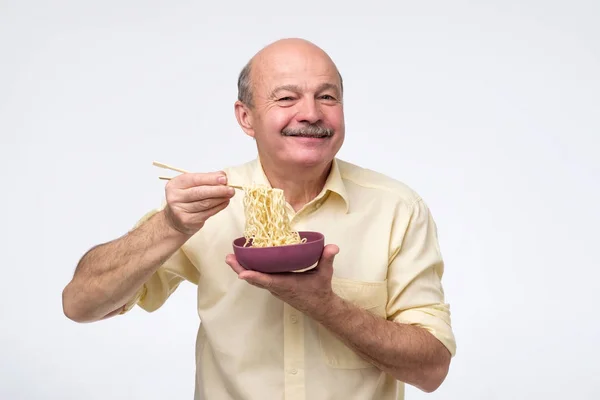 Senior bald asian man eating noodles, traditional chinese food — Stockfoto