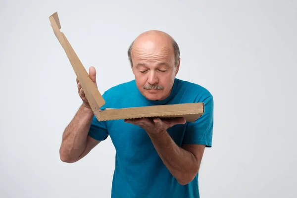 Senior man holds open box of hot pizza and looks at food. — 스톡 사진