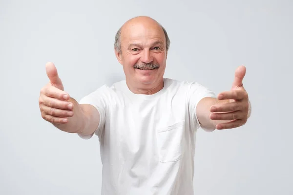 Senior man pulling hands towards camera, wanting to cuddle, smiling broadly — Stock Photo, Image