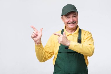 worker in cap and protective clothes pointing aside with finger