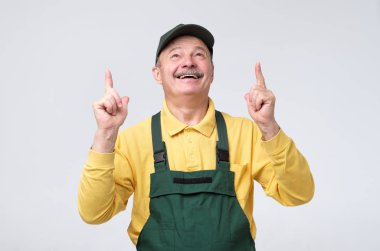 worker in cap and protective clothes pointing up with finger